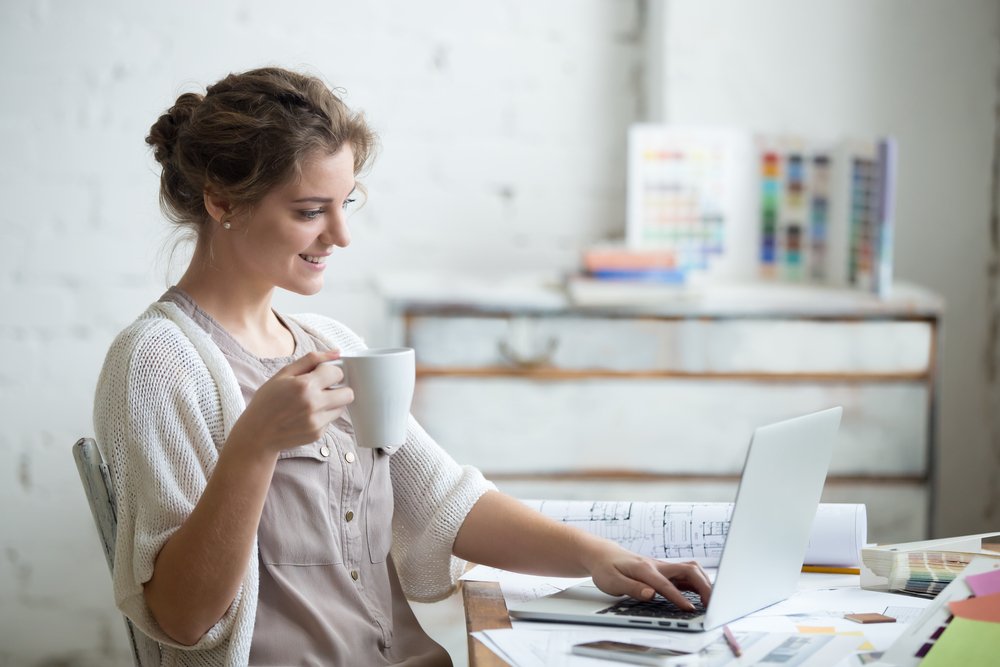 uma mulher sentada em uma mesa com um laptop e uma xícara de café