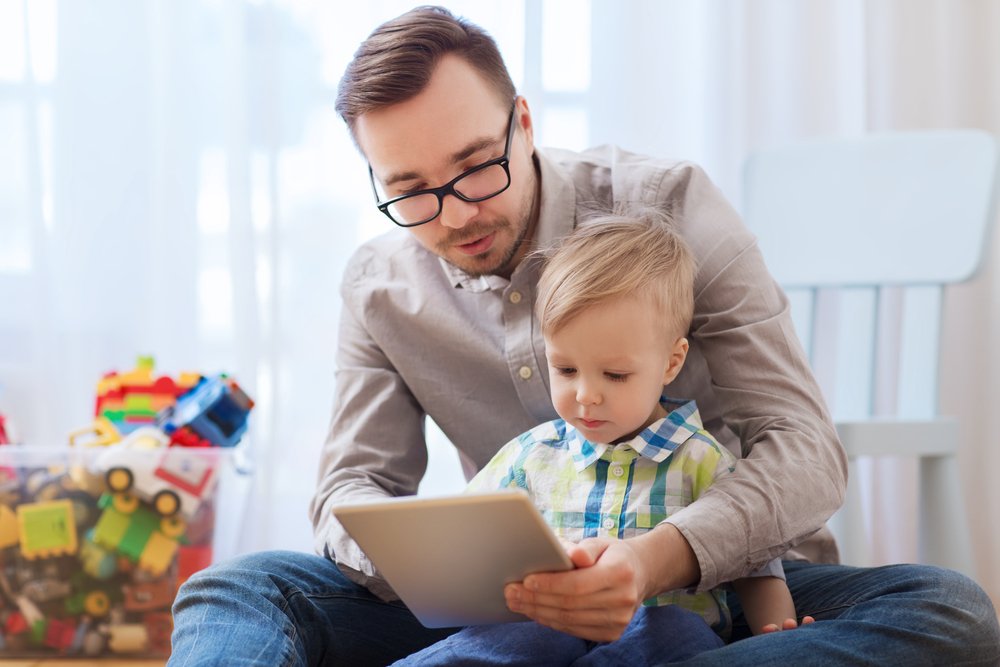 um homem está brincando com uma criança em um tablet