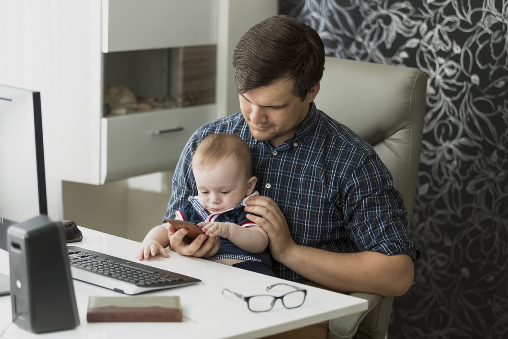 um homem sentado em uma mesa segurando um bebê