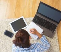 uma mulher sentada no chão trabalhando em seu laptop