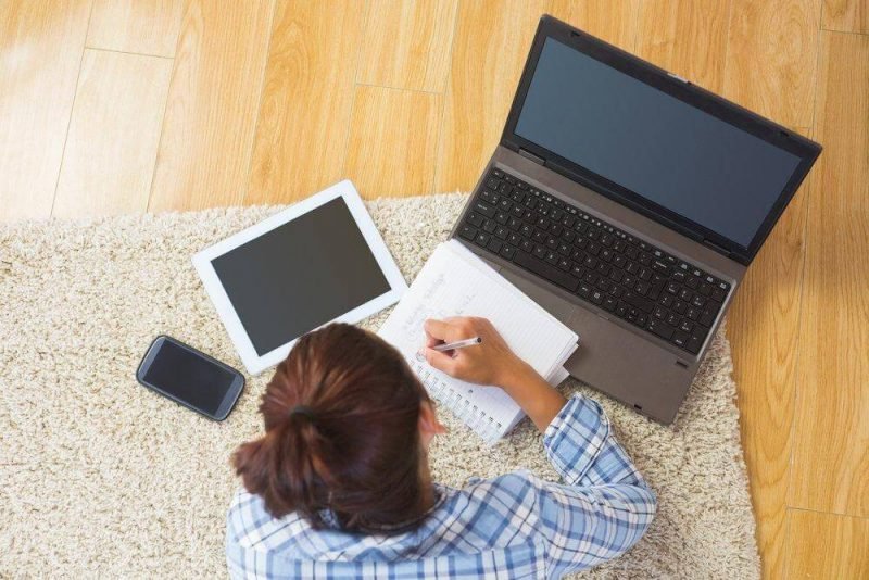 uma mulher sentada no chão trabalhando em seu laptop