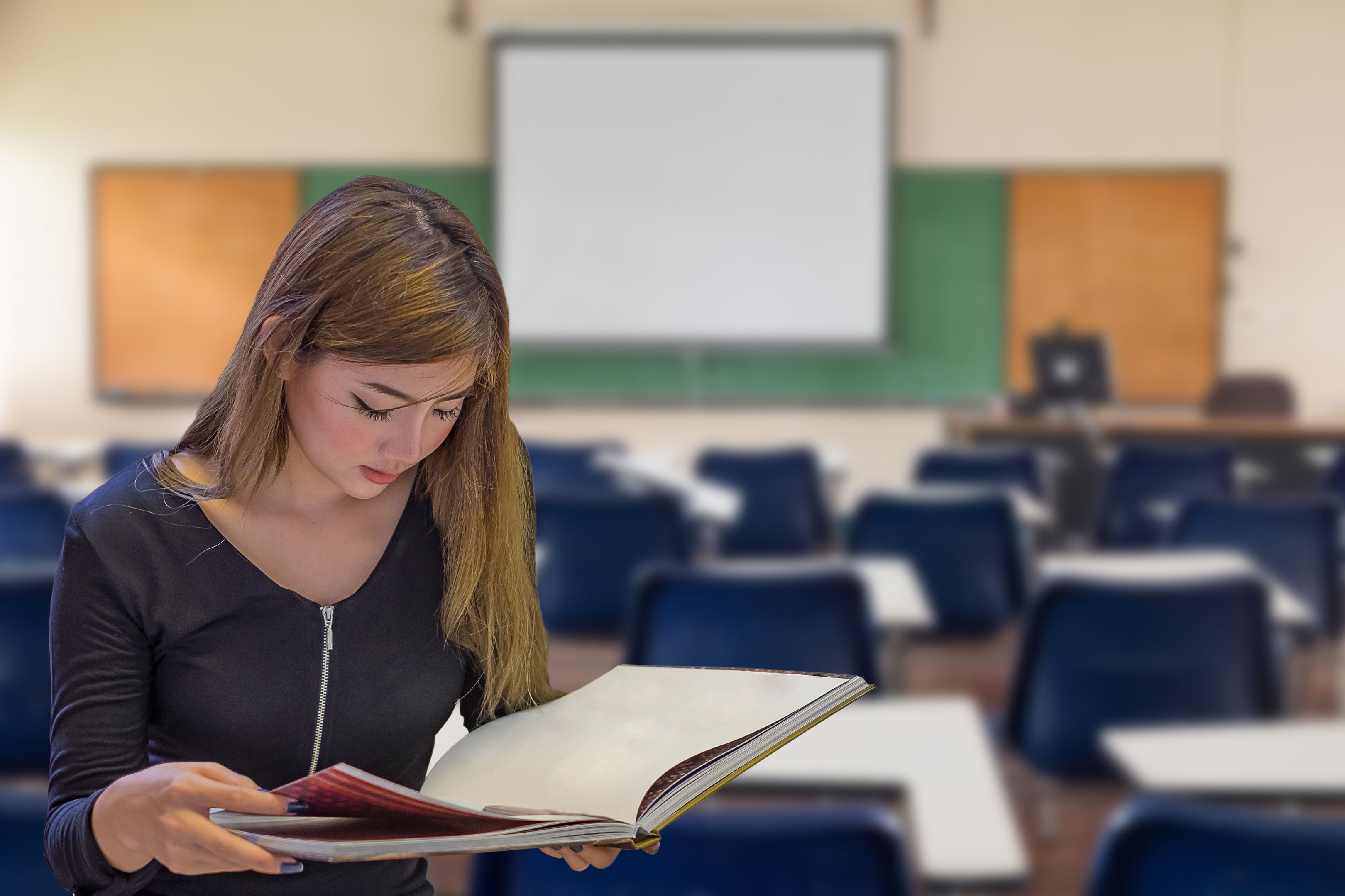uma mulher lendo um livro em uma sala de aula