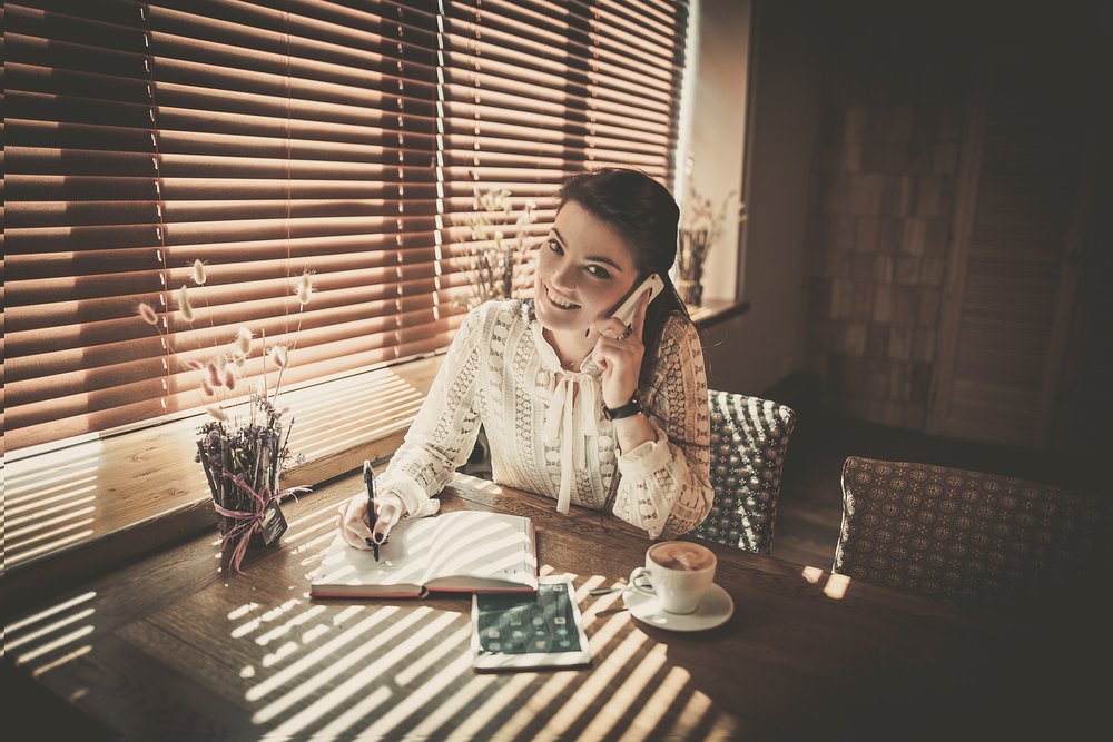 uma mulher sentada em uma mesa falando ao celular