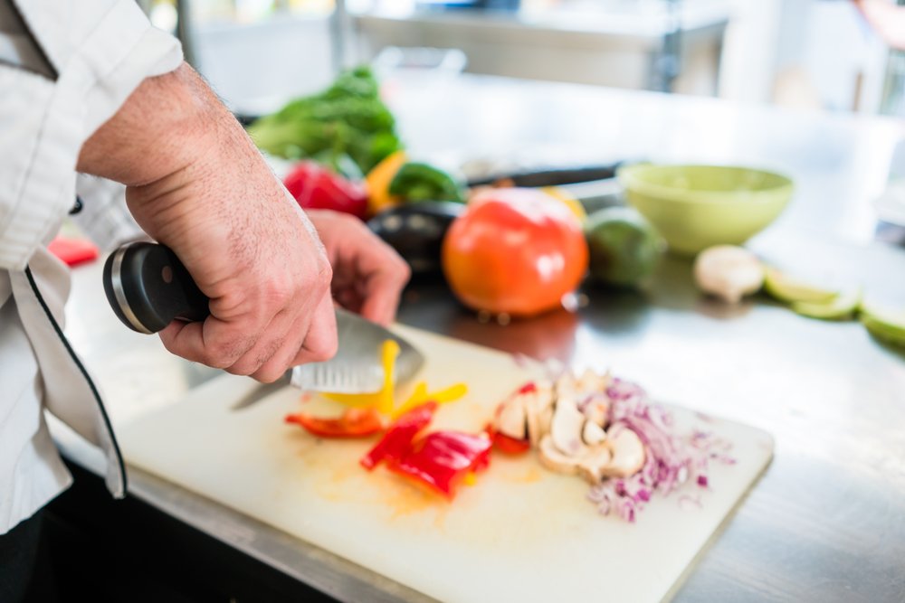 uma pessoa cortando legumes em uma tábua