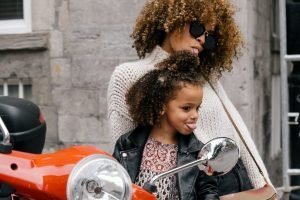 uma mulher e uma menina sentadas em uma motocicleta