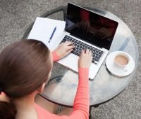uma mulher sentada em uma mesa usando um laptop