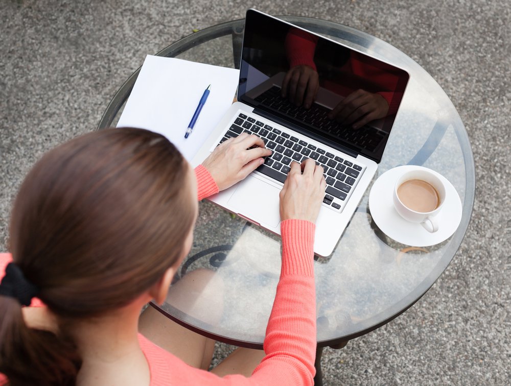 uma mulher sentada em uma mesa usando um laptop