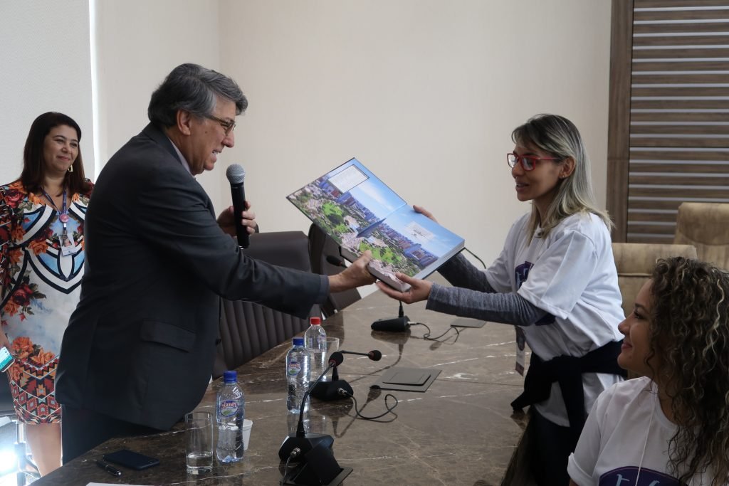 Aluna Barbara ganhando o livro sobre a história de Maringá 