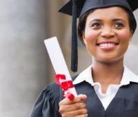 uma mulher de boné e vestido segurando um diploma