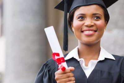 uma mulher de boné e vestido segurando um diploma