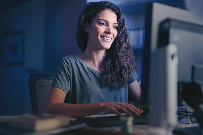 uma mulher sentada na frente de um computador sorrindo