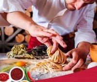 um homem com uniforme de chef preparando comida em uma mesa