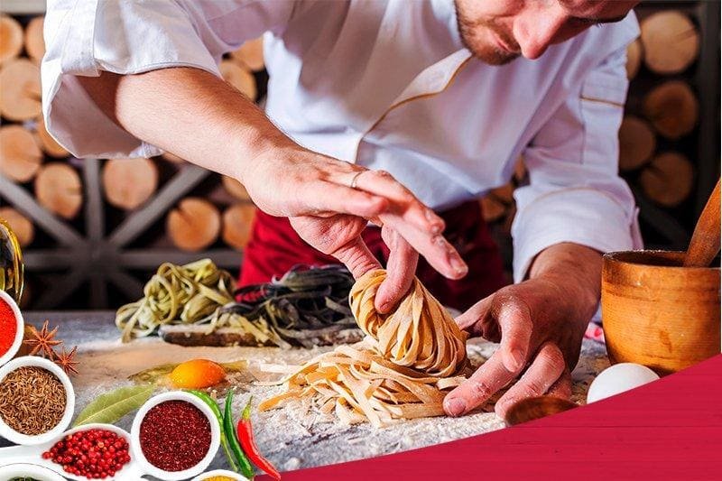 um homem com uniforme de chef preparando comida em uma mesa