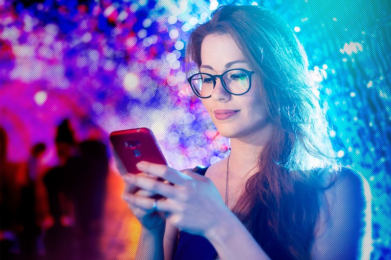 uma mulher de óculos olhando para um celular