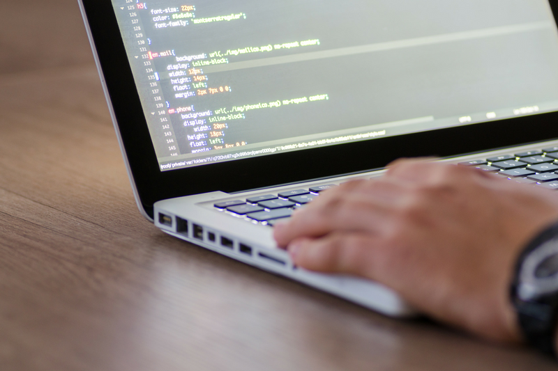 uma pessoa digitando em um laptop sobre uma mesa de madeira