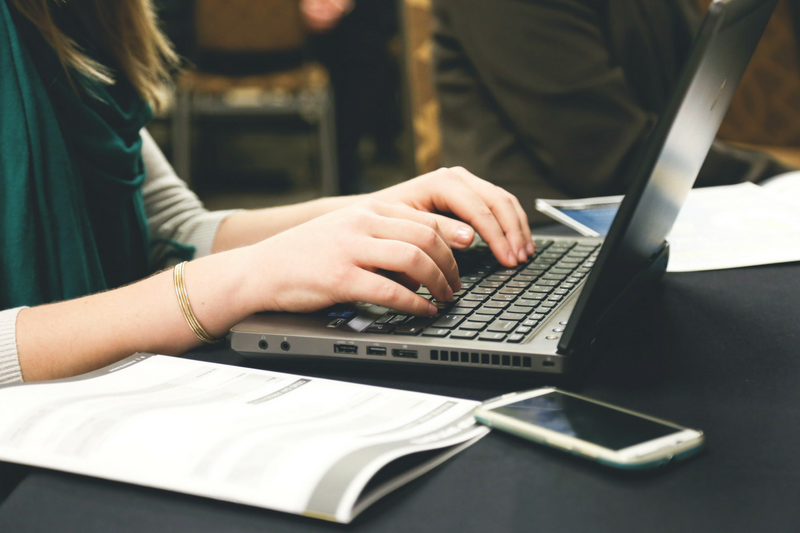 uma mulher digitando em um laptop em uma mesa