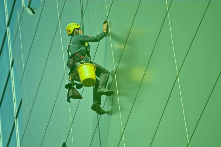 um homem subindo pela lateral de um prédio verde