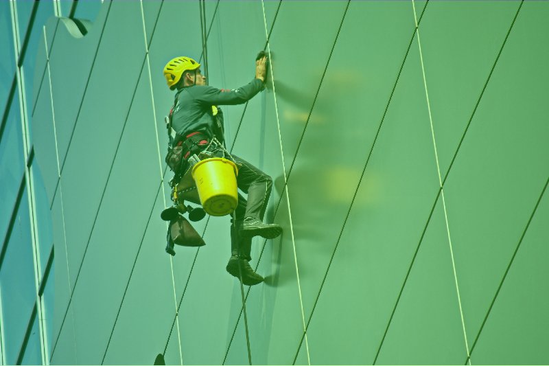 um homem subindo pela lateral de um prédio verde