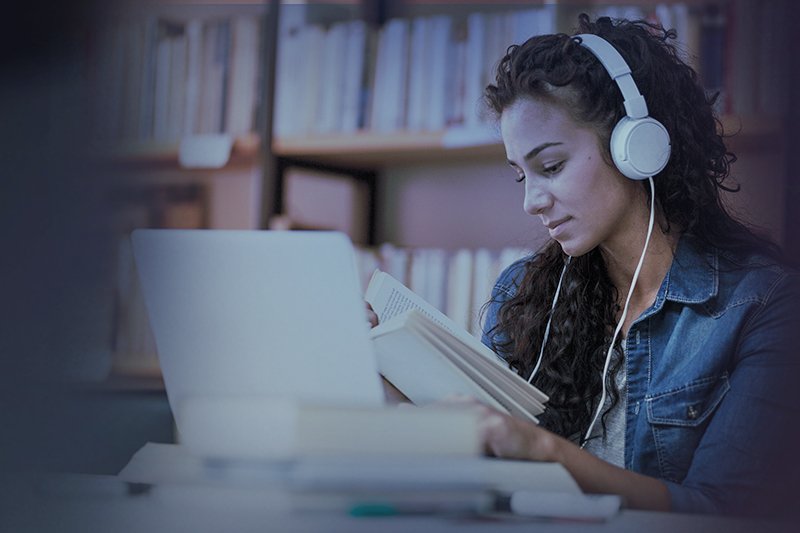 uma mulher usando fones de ouvido e lendo um livro