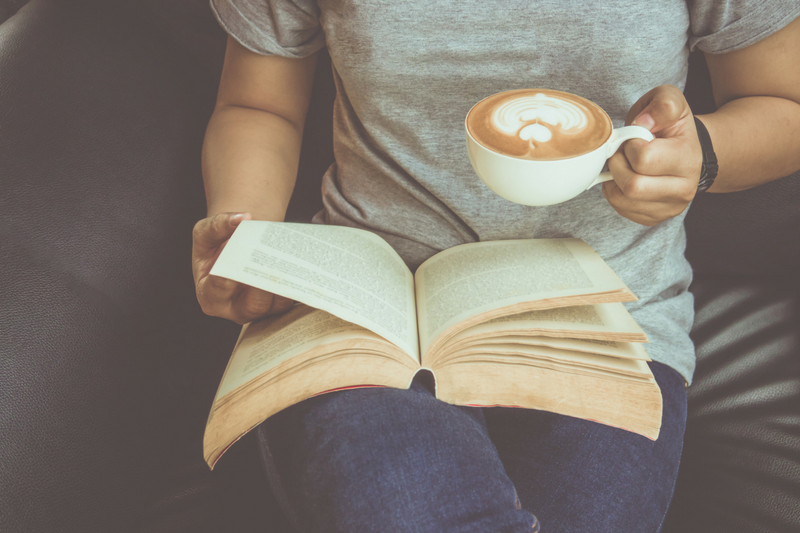 uma mulher está segurando um livro e uma xícara de café