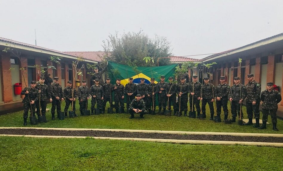 Foto dos alunos do Núcleo de Preparação de Oficiais da Reserva do Exército Brasileiro e do autor deste trabalho, abaixado no centro, com as mudas de árvores de grande porte 