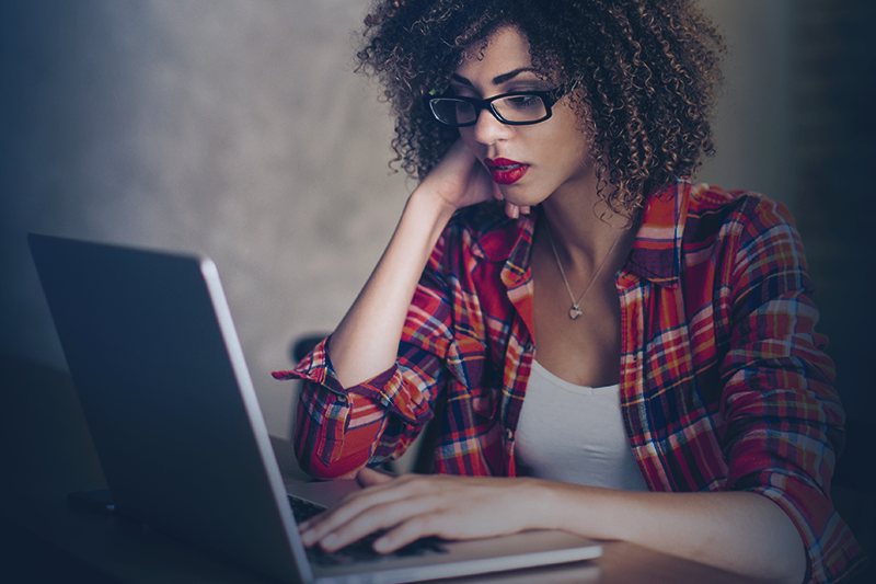 uma mulher sentada em uma mesa usando um laptop