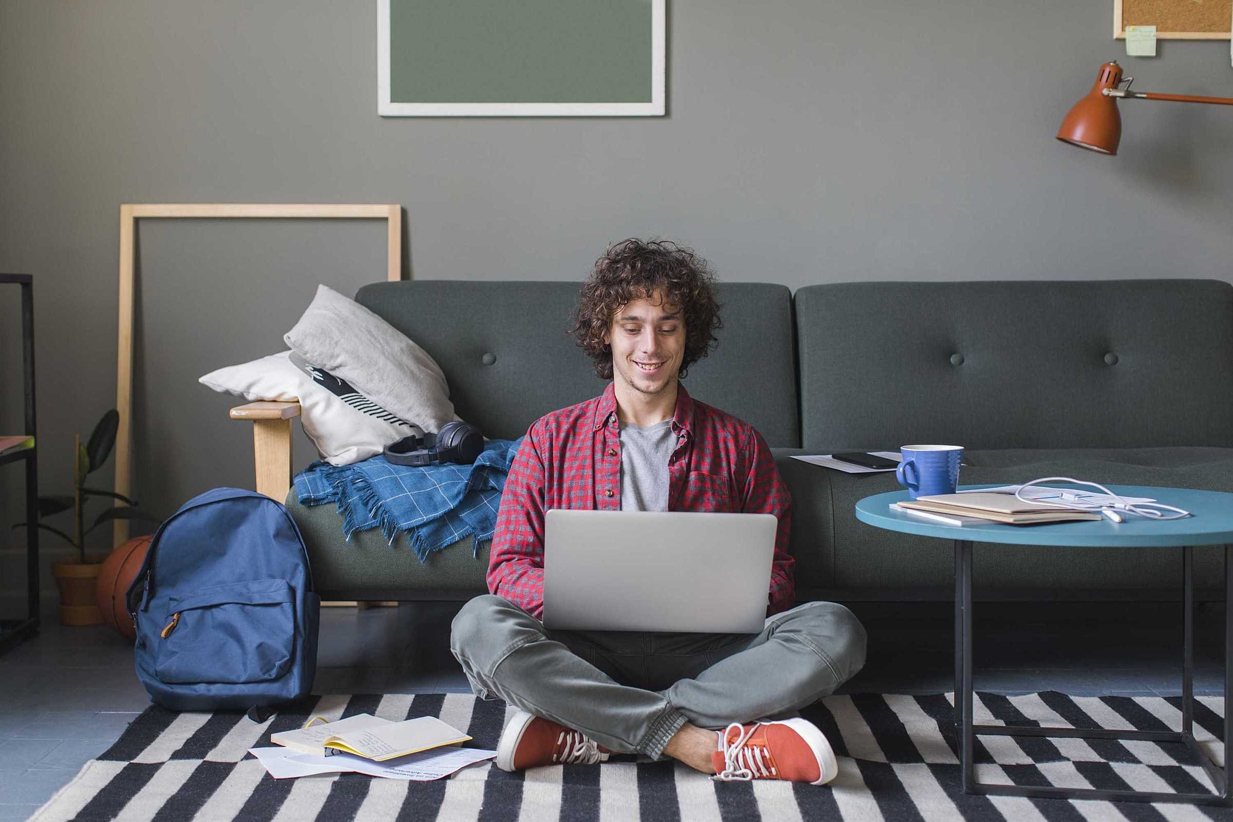 um homem sentado no chão usando um laptop