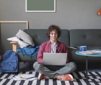 um homem sentado no chão usando um laptop