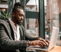 Homem negro trabalhando em laptop em um ambiente moderno, concentrado e produtivo. Ideal para ilustrar o tema de trabalho remoto e produtividade.