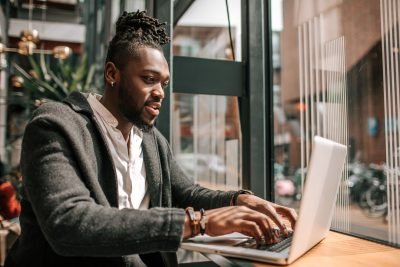Homem negro trabalhando em laptop em um ambiente moderno, concentrado e produtivo. Ideal para ilustrar o tema de trabalho remoto e produtividade.