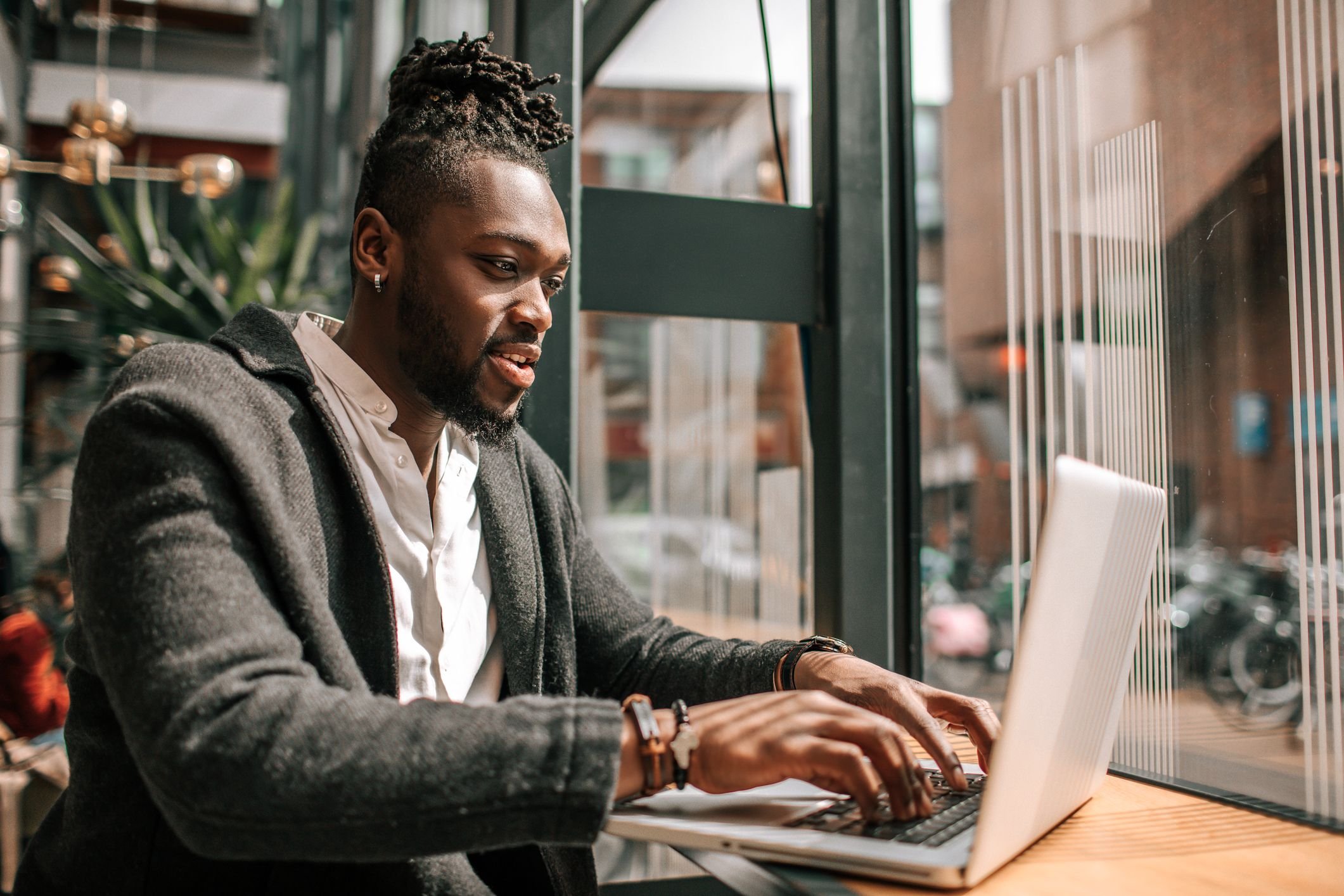 Homem negro trabalhando em laptop em um ambiente moderno, concentrado e produtivo. Ideal para ilustrar o tema de trabalho remoto e produtividade.