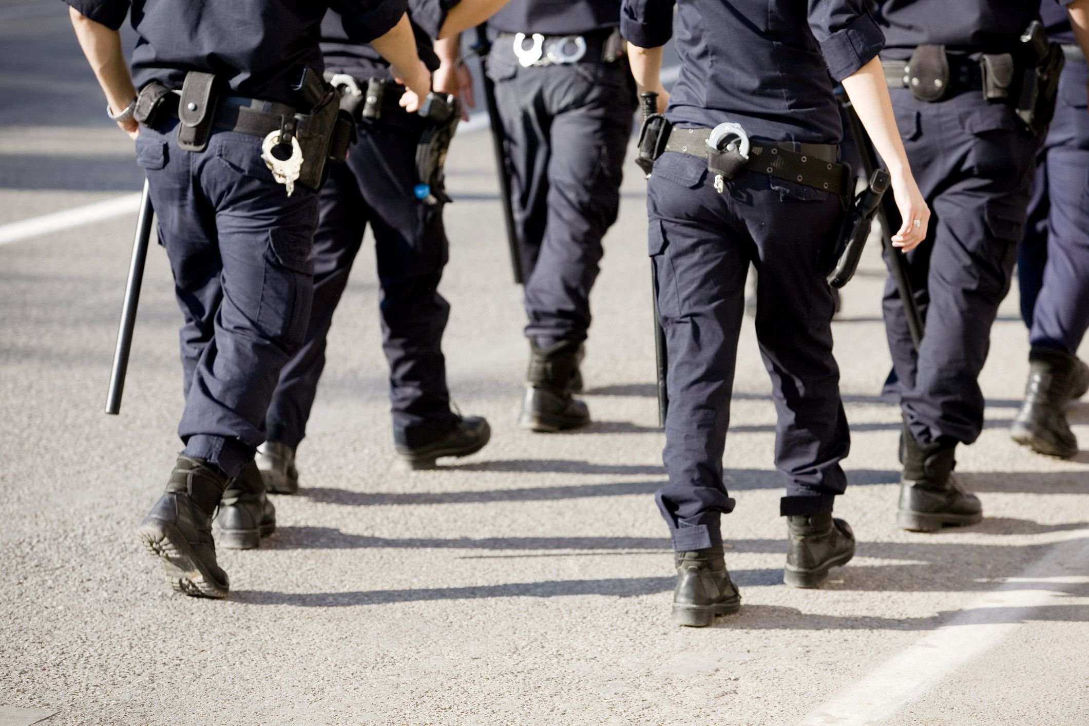Imagem de policiais em uniforme, caminhando em direção ao alvo. A cena demonstra a atuação das forças de segurança pública em um ambiente urbano.