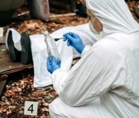 Profissional forense analisando evidências em cena de crime, com botellas e objetos identificados, em um cenário misterioso.