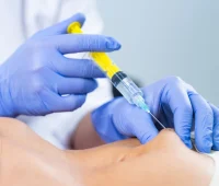 Profissional de saúde aplicando injeção com seringa em paciente, mostrando a importância de cuidados médicos e procedimentos de saúde.