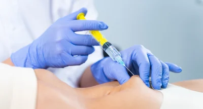 Profissional de saúde aplicando injeção com seringa em paciente, mostrando a importância de cuidados médicos e procedimentos de saúde.