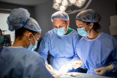 Equipe de cirurgiões realizando procedimento em centro cirúrgico, ilustrando a área da medicina voltada para Cirurgia Geral.