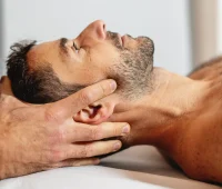 Homem recebendo massagem terapêutica, foco na técnica de massagem para alivio de tensão cervical, enfatizando o cuidado e relaxamento.