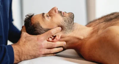 Homem recebendo massagem terapêutica, foco na técnica de massagem para alivio de tensão cervical, enfatizando o cuidado e relaxamento.