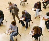 Grupo de estudantes realizando uma prova em sala de aula, com foco no processo de aprendizado e concentração dos alunos durante o exame.
