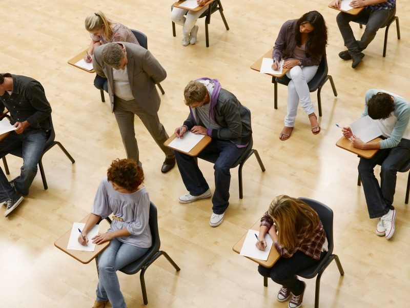 Grupo de estudantes realizando uma prova em sala de aula, com foco no processo de aprendizado e concentração dos alunos durante o exame.