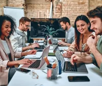 Grupo de pessoas trabalhando em equipe em um escritório moderno, usando laptops e colaborando em projetos, ilustrando o conceito de trabalho em equipe e produtividade.