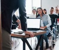 Sala de aula com estudantes participando de uma aula interativa, enquanto o professor conduz a explicação. A imagem representa MBA o que é, destacando o ambiente acadêmico e a troca de conhecimento na formação executiva.
