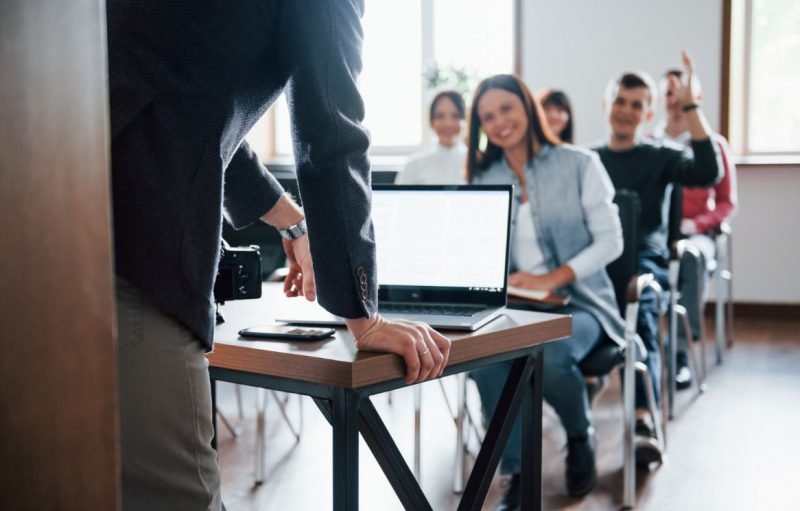 Sala de aula com estudantes participando de uma aula interativa, enquanto o professor conduz a explicação. A imagem representa MBA o que é, destacando o ambiente acadêmico e a troca de conhecimento na formação executiva.