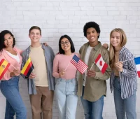 Grupo de jovens de diferentes origens culturais segurando bandeiras de diversos países, demonstrando diversidade e amizade internacional.