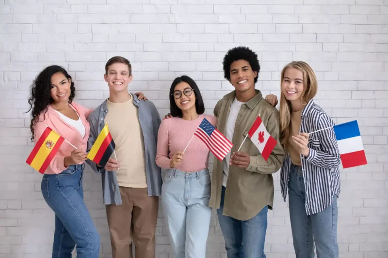 Grupo de jovens de diferentes origens culturais segurando bandeiras de diversos países, demonstrando diversidade e amizade internacional.