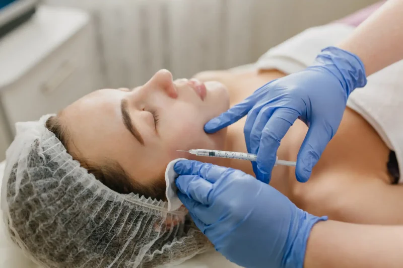 Paciente recebendo aplicação de botox facial por um profissional de saúde usando luvas médicas em ambiente clínico