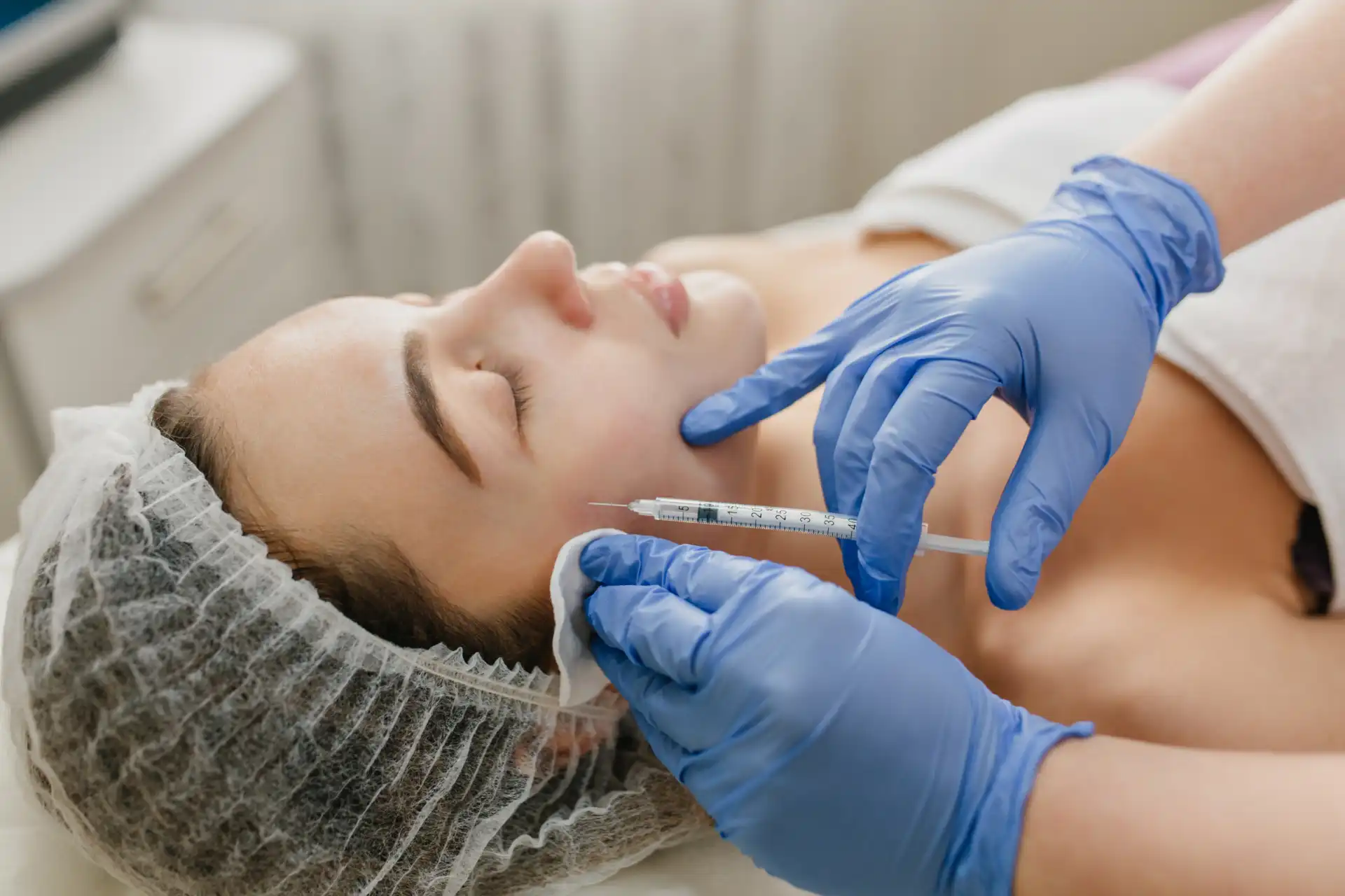 Paciente recebendo aplicação de botox facial por um profissional de saúde usando luvas médicas em ambiente clínico
