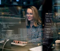 Jovem mulher programadora trabalhando em ambiente de tecnologia, focada em desenvolvimento de software e inteligência artificial, com código na tela.