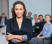 Gestora de recursos humanos sorridente em reunião de equipe, representando liderança e gestão de pessoas no ambiente corporativo.
