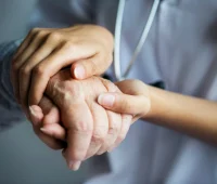 Mãos de um profissional de saúde segurando a mão de um paciente, simbolizando cuidado médico, assistência na saúde, empatia, apoio e tratamento.